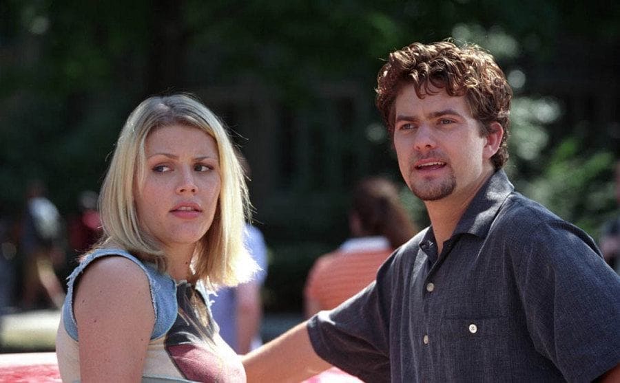 Busy Philipps and Joshua Jackson standing near a car in a scene from Dawson’s Creek
