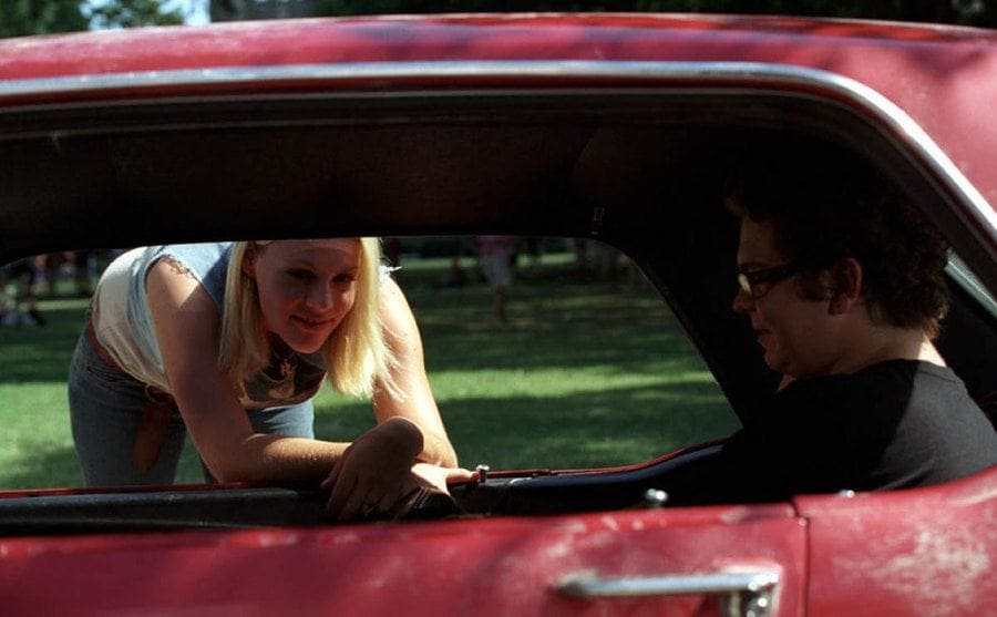 Busy Philipps leaning into a red car with Jack Osbourne in the back
