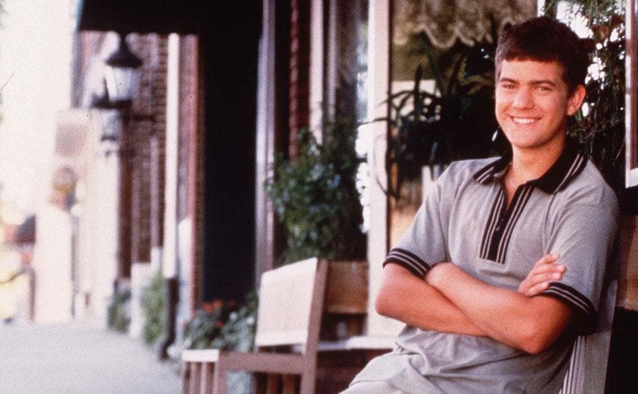 Joshua Jackson leaning on a chair outside of a restaurant in a promotional photograph for Dawson’s Creek