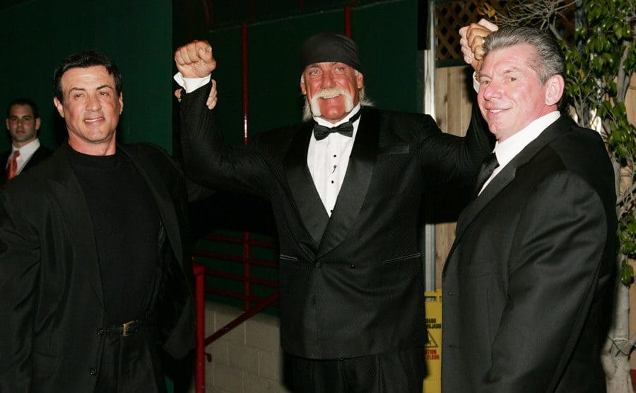 Sylvester Stallone, Hulk Hogan, and Vince McMahon posing together 