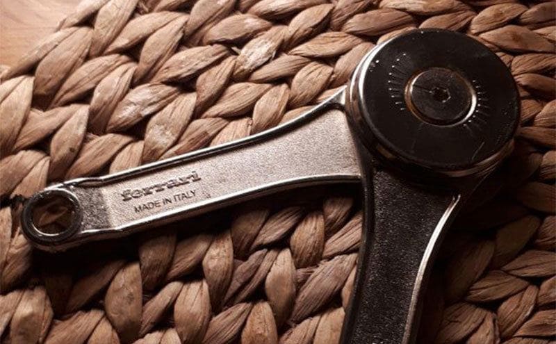 A cabinet hinge placed on a table, you can see the ‘Ferrari made in Italy etching on the handles.