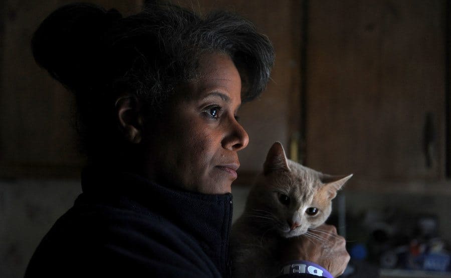Debi Thomas holding her cat and looking away from the camera