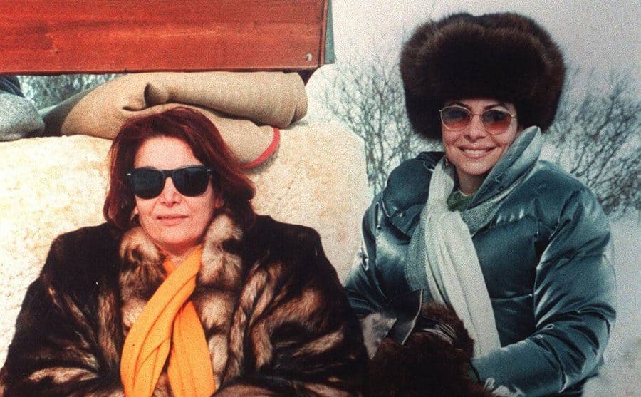 Pina Auriemma and Patrizia Reggiani are smiling while on top of the snowy mountains. 