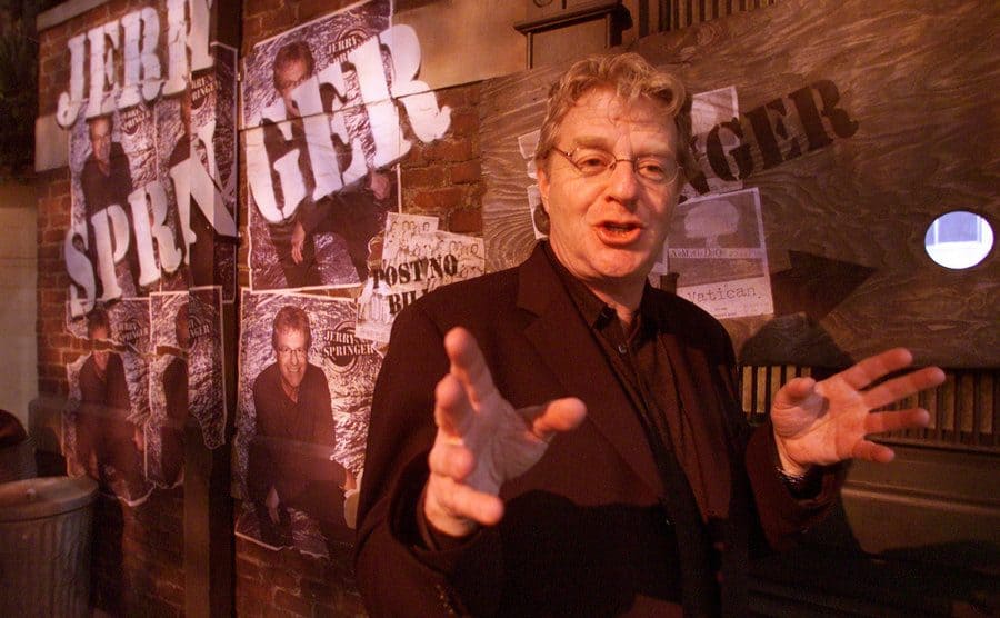Jerry Springer making hand gestures while talking on the set of The Jerry Springer Show