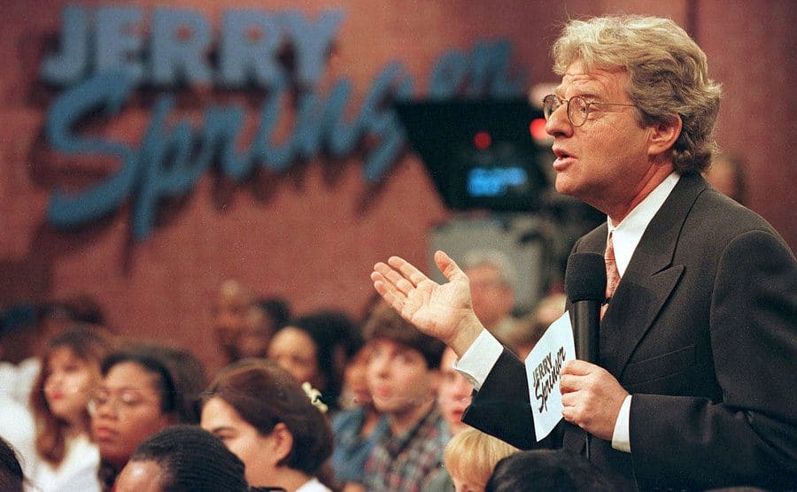Jerry Springer gesturing with his hand from next to the audience
