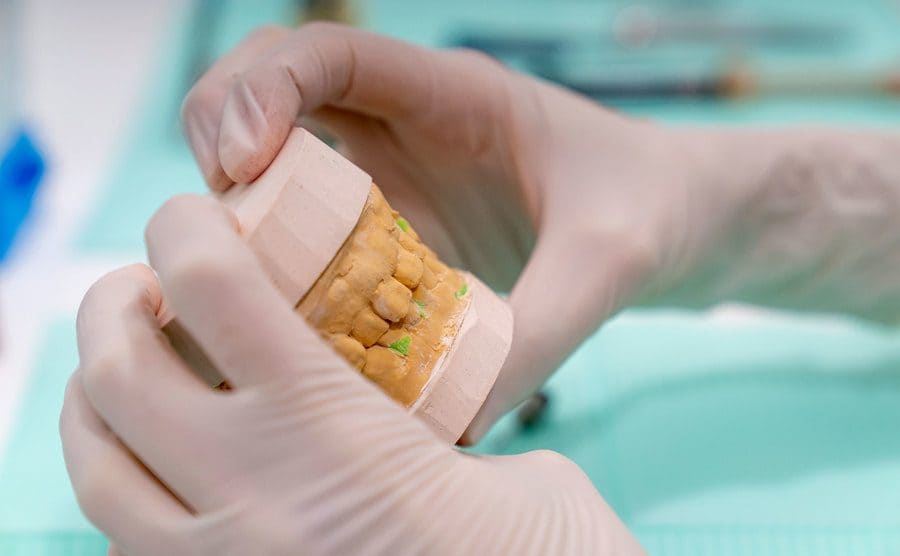 Cropped hands of a dental technician working on making a teeth mold.