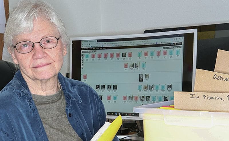 Margaret Press is sitting by her computer and a box filled with cold case files.