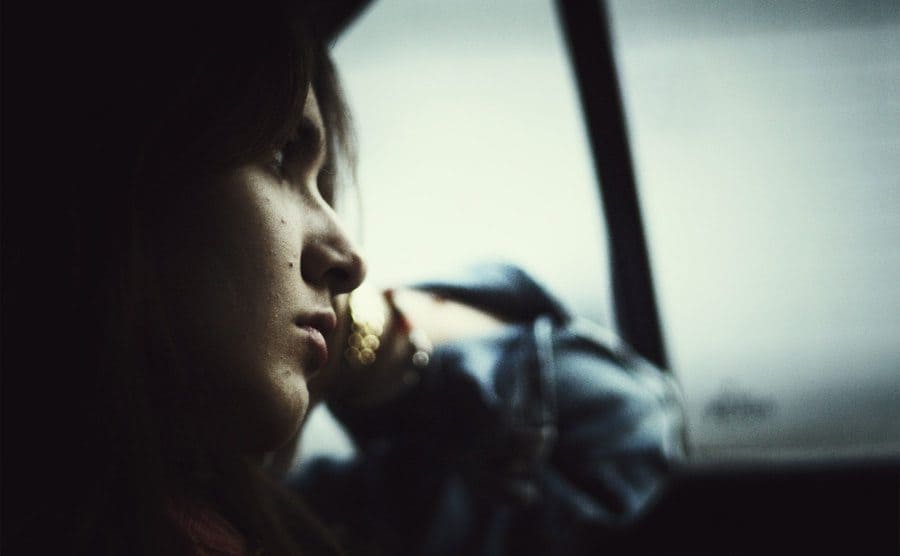 A sad-looking girl staring out the car window.