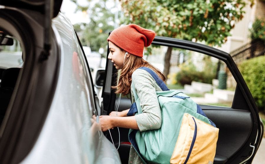 A teenage girl getting into a car.