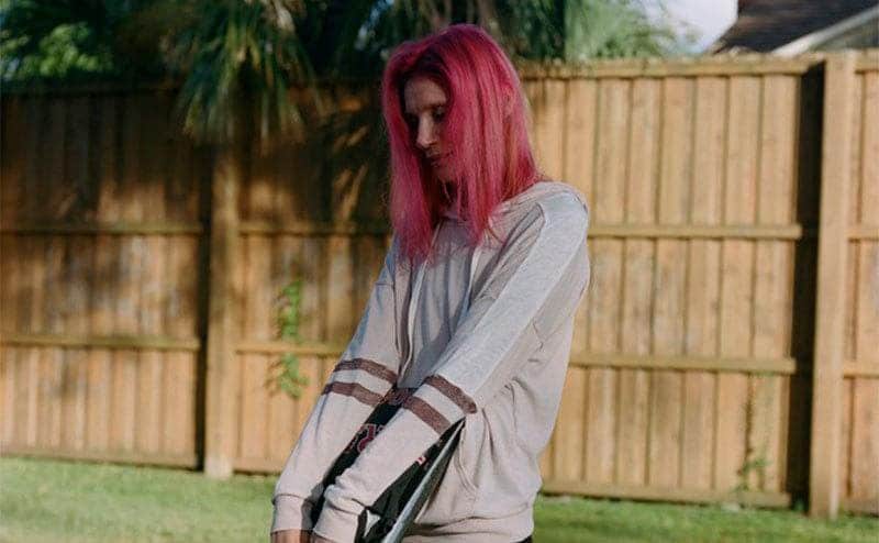 Bobbie is standing in her backyard holding her old yearbook that still has photos of Dana.