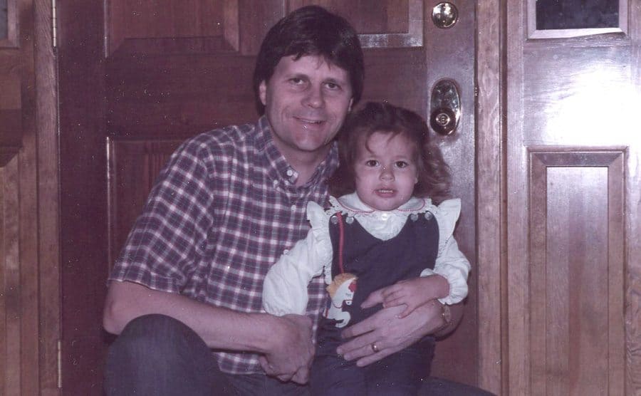 Ali Kemp, at a very young age, being held by her father.