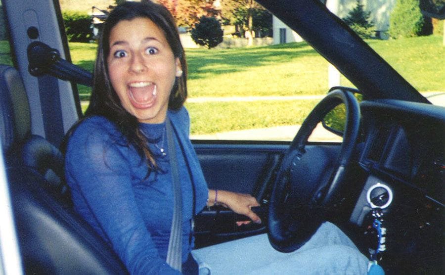 Ali Kemp making a surprised face while sitting in her car.
