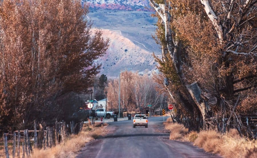 A pickup truck driving down a rural dirt road