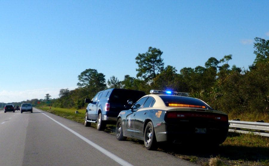 A police car making a traffic stop on the side of the road.
