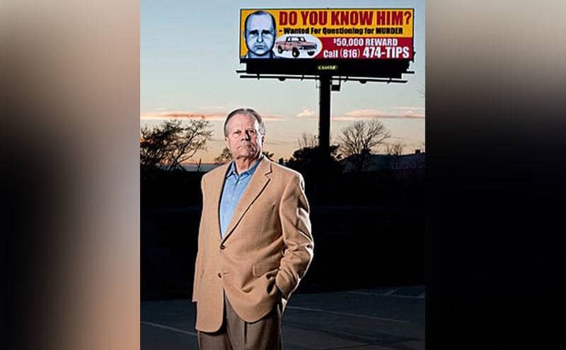 Roger Kemp standing in front of the billboard he rented.