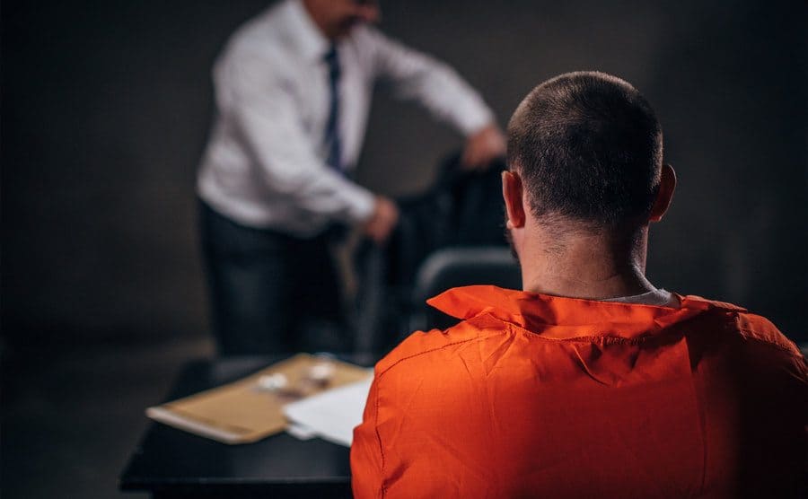 A detective investigating a prisoner in a dark investigation room.