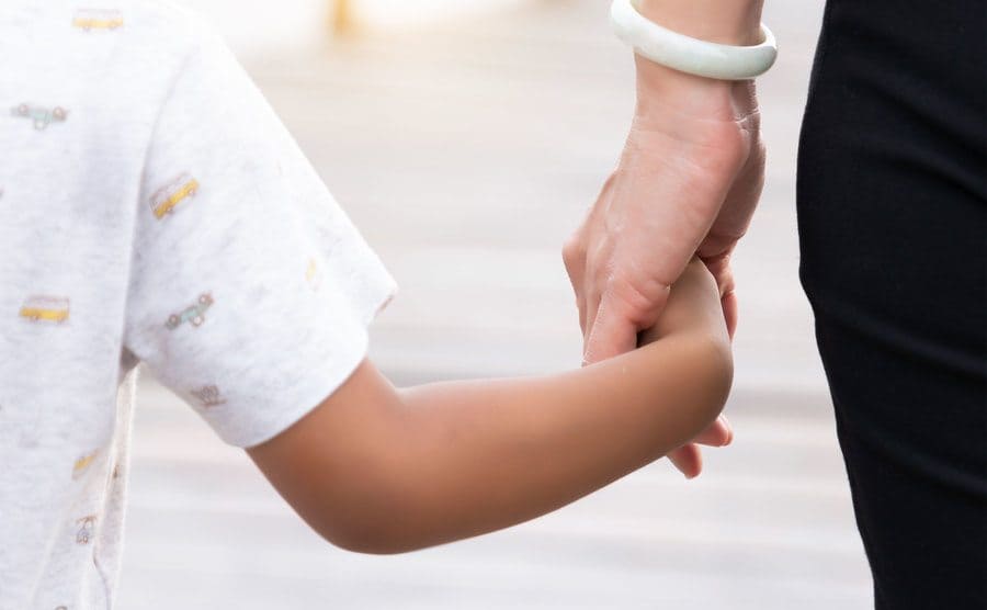 Rearview of a child holding his mother’s hand. 