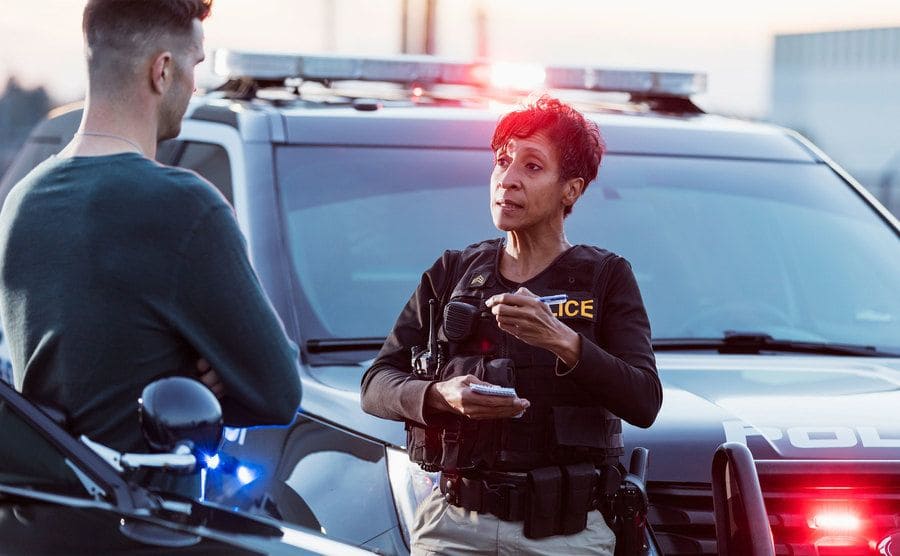 A policewoman is taking a statement from a civilian on the street. 