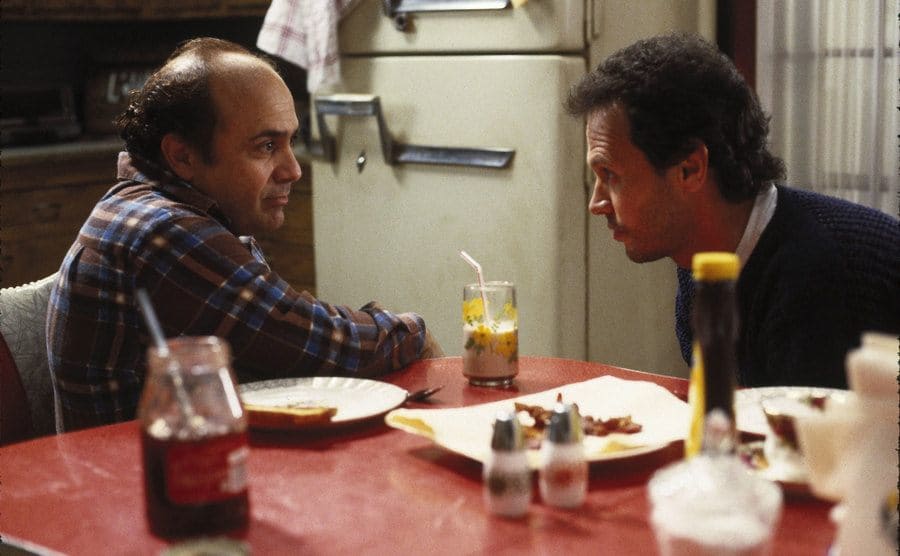 Danny Davito and Billy Crystal, as Owen and Larry, sit at the kitchen table making a plan. 