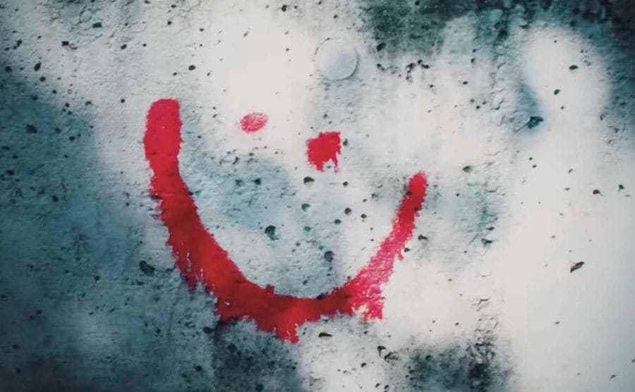 A smiley face graffitied onto a wall.