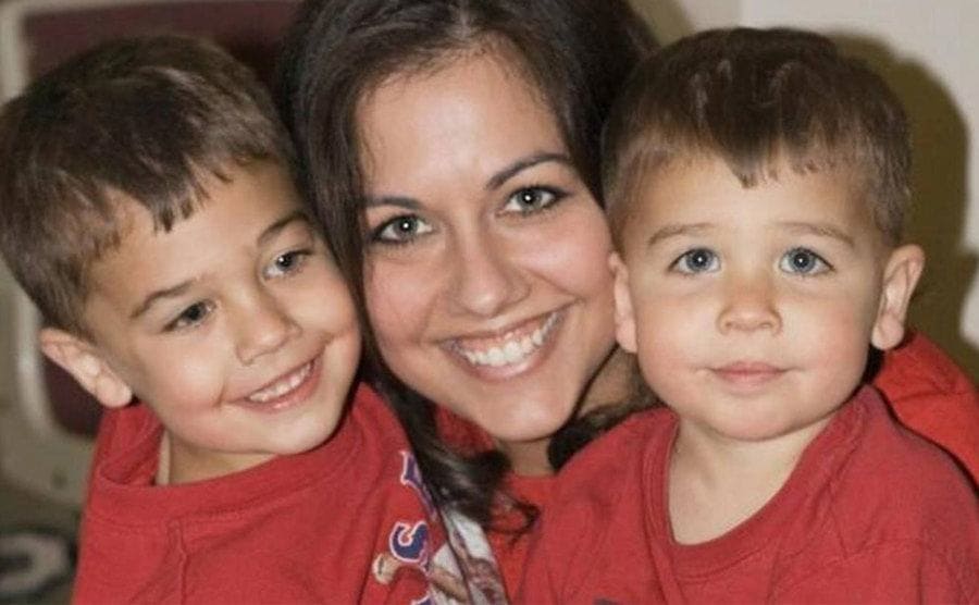Vashti is holding her kids one on each side of her lap.