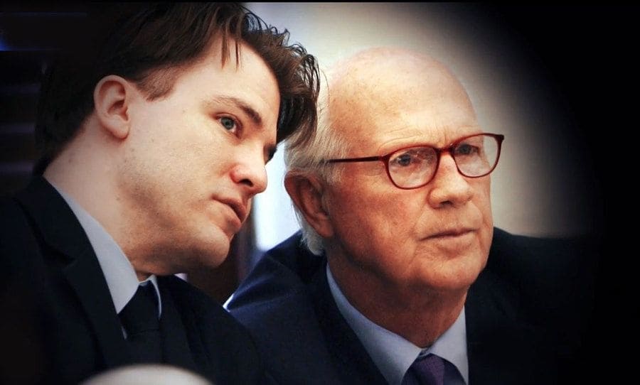 Brett is whispering into his lawyer's ear in the courtroom.