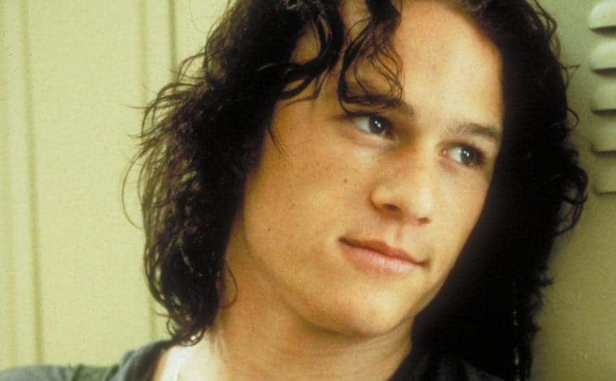 Heath Ledger is leaning on a school locker in a scene from ’10 Things I Hate About You’.