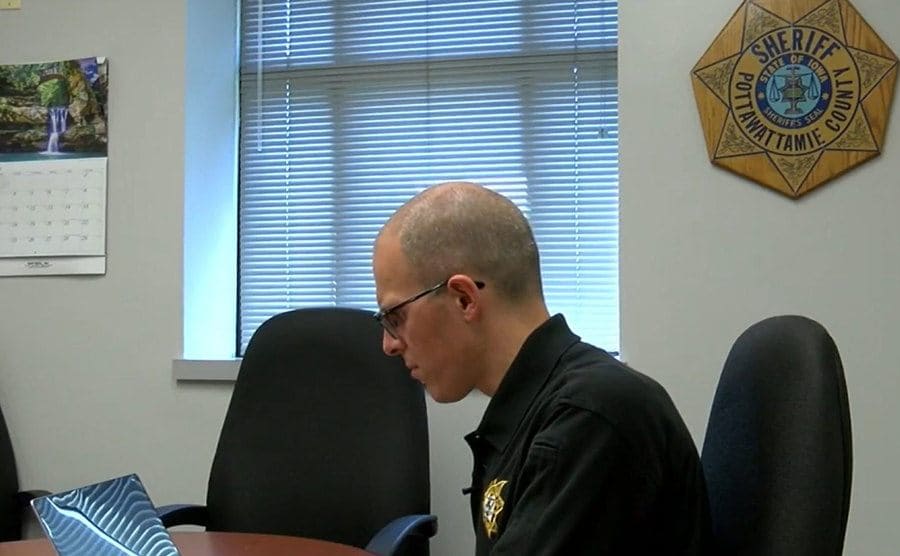 A police officer is sitting in his office going through the investigation process.