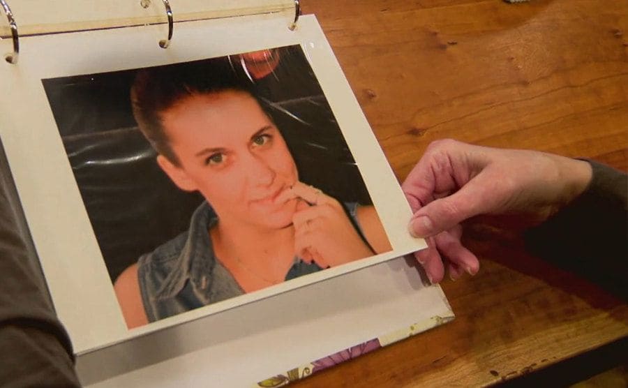 Raney is flipping the pages of a photo album with pictures of Carie.