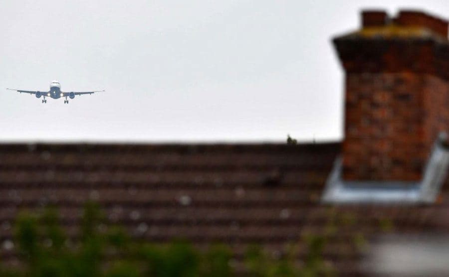 A plane is flying over rooftops.