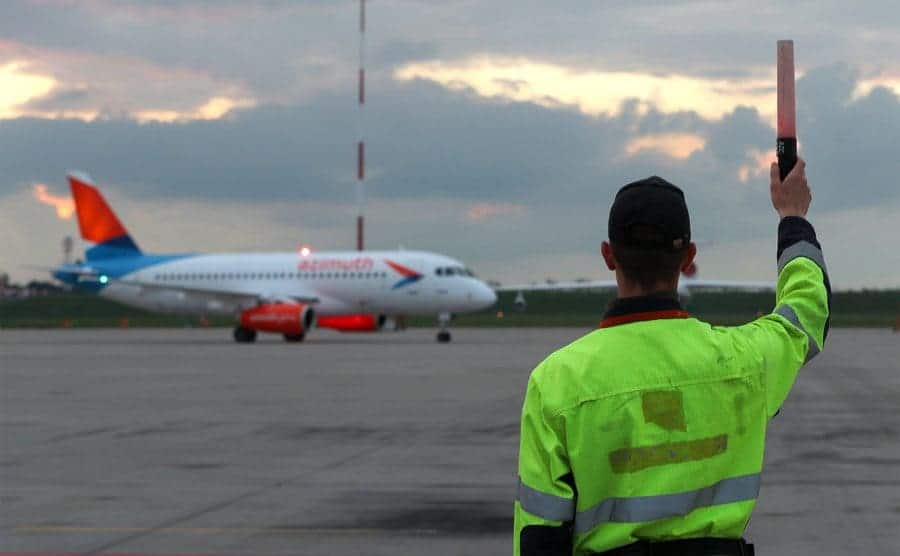 A signalman waves down a plane after it lands.