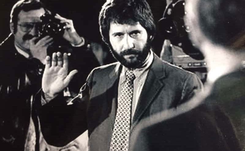Frank Serpico is raising his hand at a press conference.