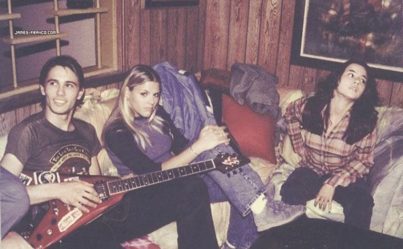 James Franco plays an electric guitar on set beside Busy and Linda.