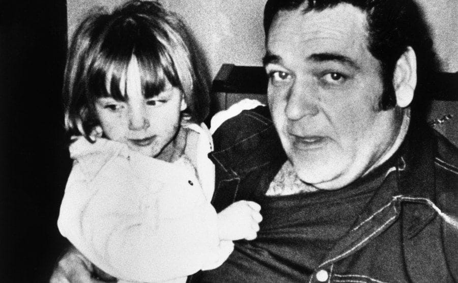 Ken Rex McElroy sits for a family photo as he holds his young daughter, Tina.