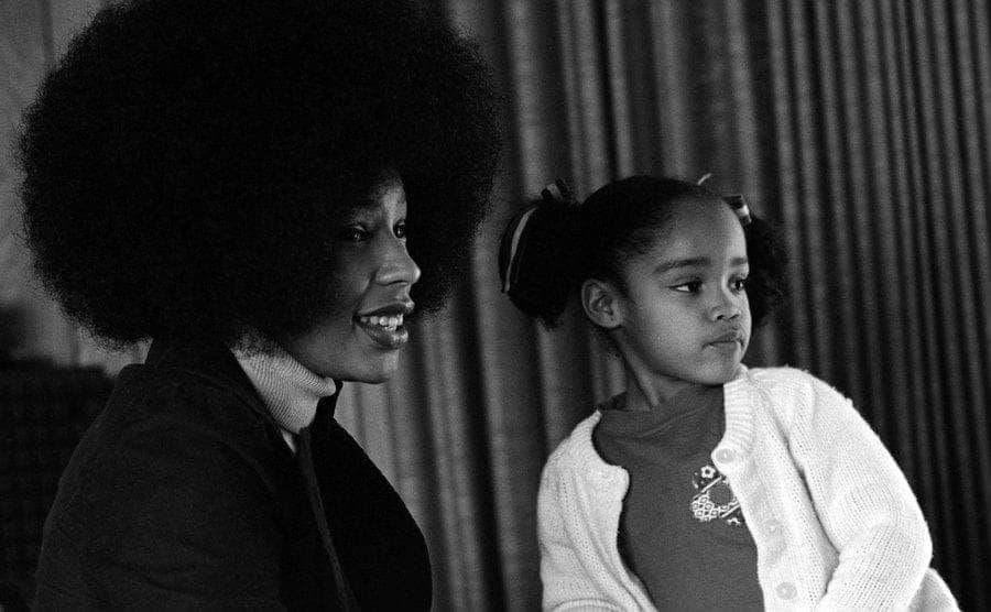 Marguerite Whitley and young child Arnelle Simpson are posing for a portrait at home.