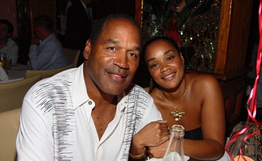 O.J. Simpson and Arnelle are posing for a photo at a restaurant during a birthday celebration.