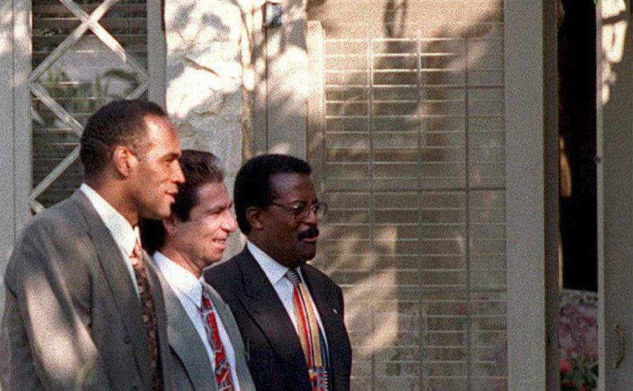 O.J. Simpson walks with Robert Kardashian and his lead attorney past one of the entrances to his house.