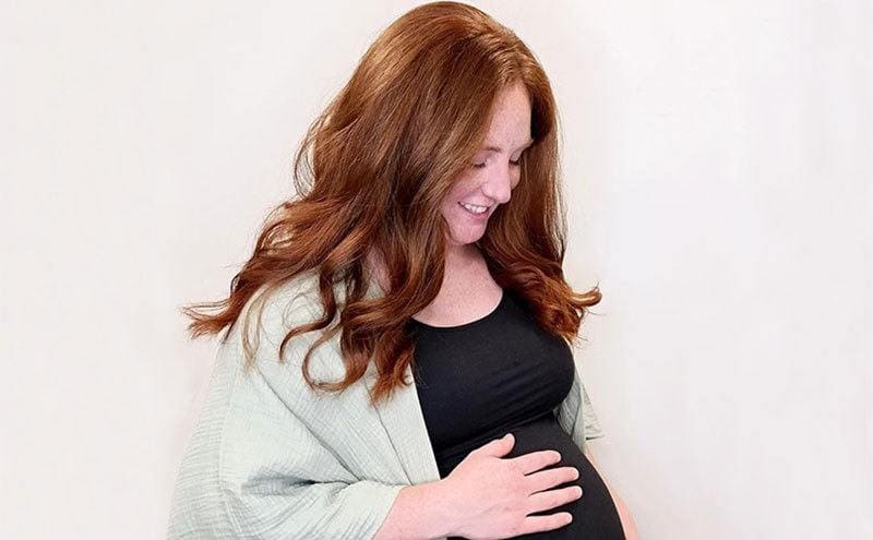 A pregnant Chelsea touches her belly.