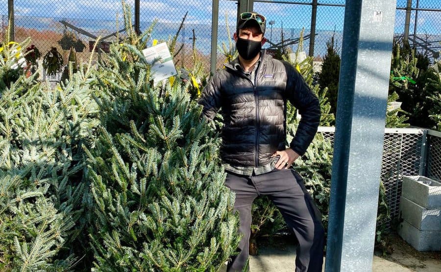Kane is posing next to a Christmas tree.