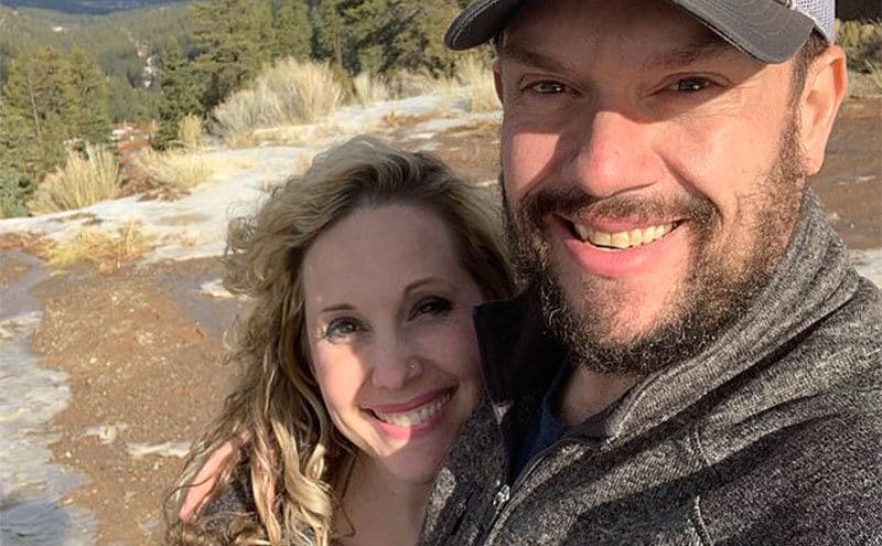 Cecily and Jason smile at the camera during a hiking trip.