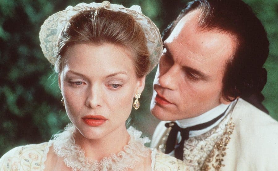 An 18th century John Malkovich is whispering into Michelle Pfeiffer’s ear.