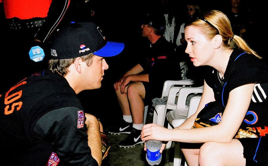 Ryan Reynolds and Melissa Joan Hart talk during a baseball game.