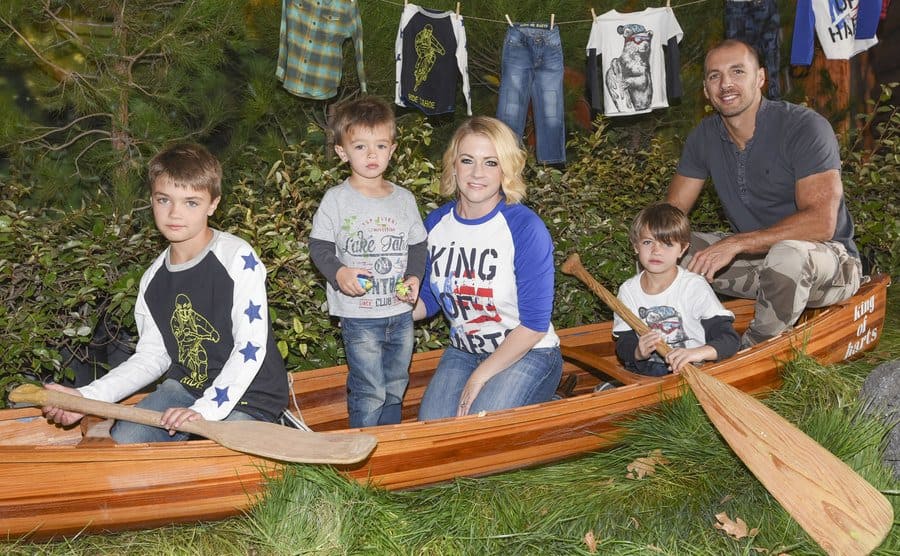 Melissa Joan Hart poses sitting in a canoe with her husband and three kids.