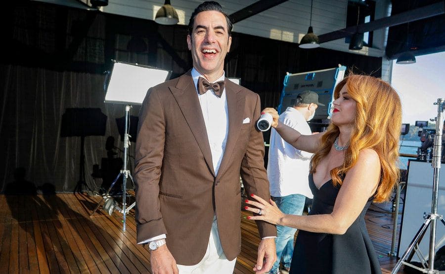 Sacha Baron Cohen and Isla Fisher make jokes as they pose for the press at the Oscars.