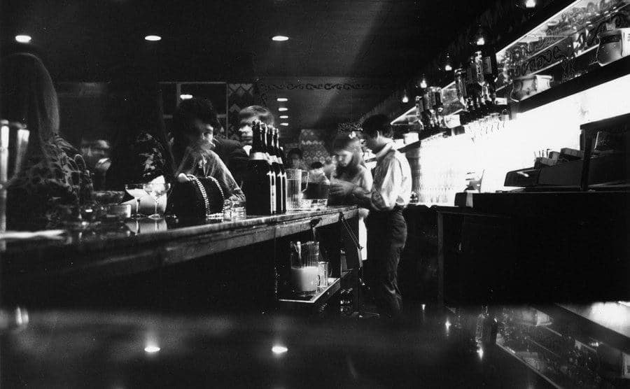 People are drinking at the bar of a nightclub.