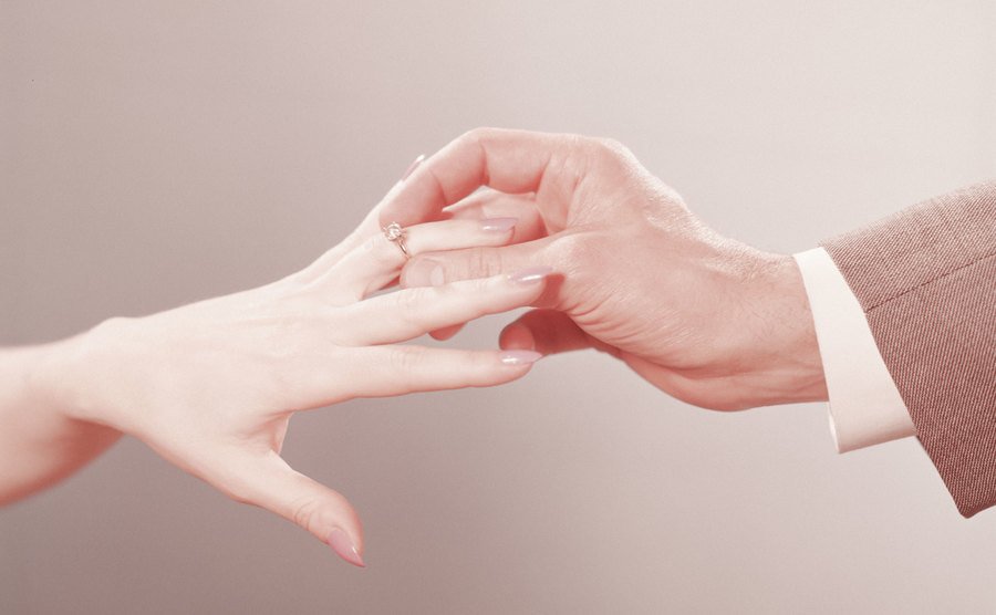 A man is placing an engagement ring on a woman’s finger.