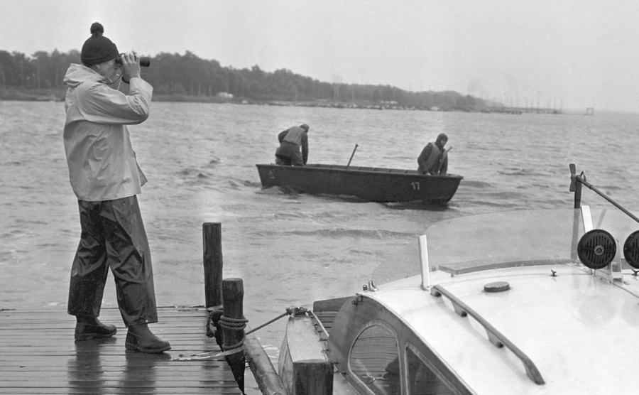 A man uses binoculars to search the lake.