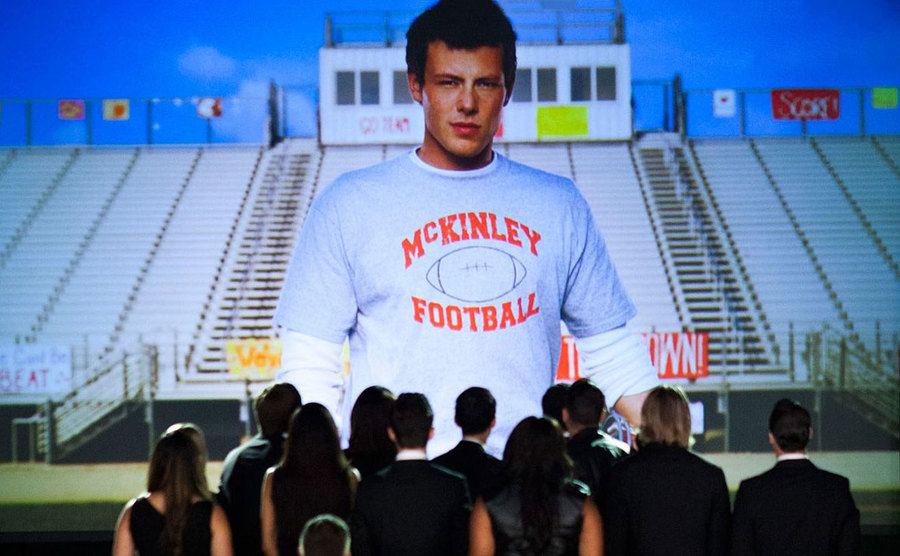 A scene from “The Quarterback” episode showing the cast glancing at a photo of Cory (Finn).