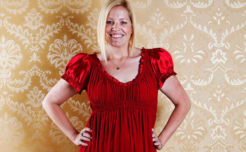 Nancy Motes in a red dress and her hands on her hips.