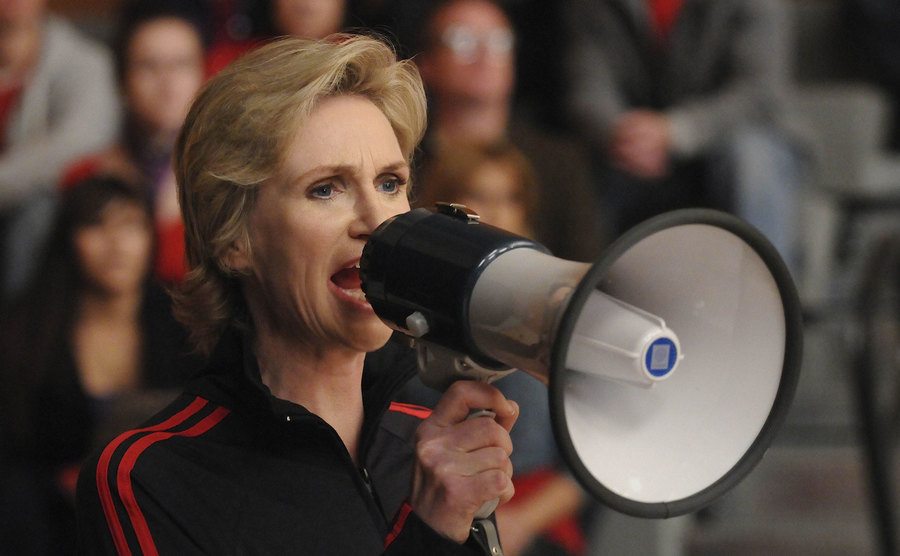 Jane Lynch yelling into a megaphone.